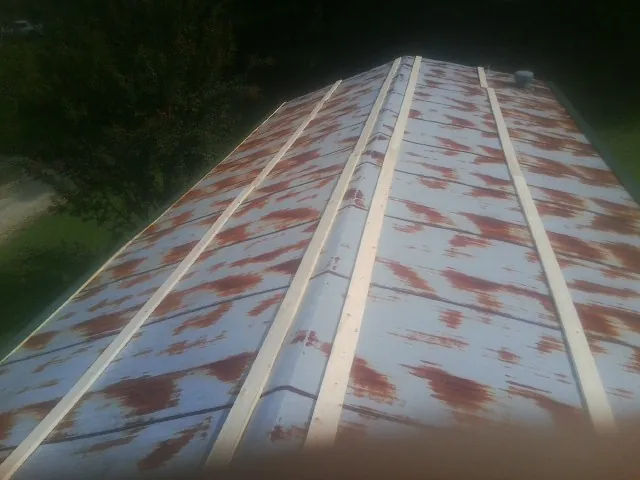 Rusted metal roof panels with new wood purlins before replacement — Storm Damage Roof Repair in Neosho by Roofing Brothers