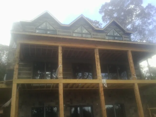Dormers and porch framing on a large log home under construction — Roof Coating work by our crew in Neosho